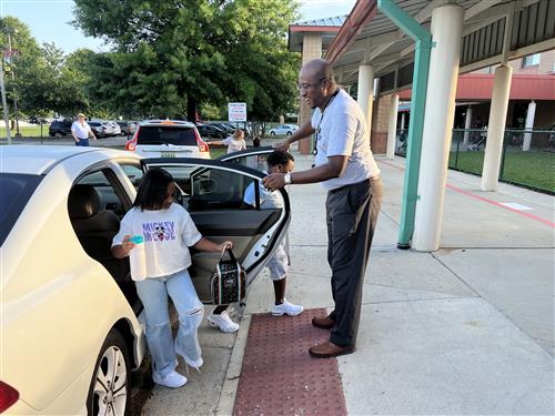 Board member Travis Cummings working car line at Horizon Elementary